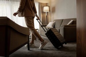 A person walking through a living room with a rolling suitcase.